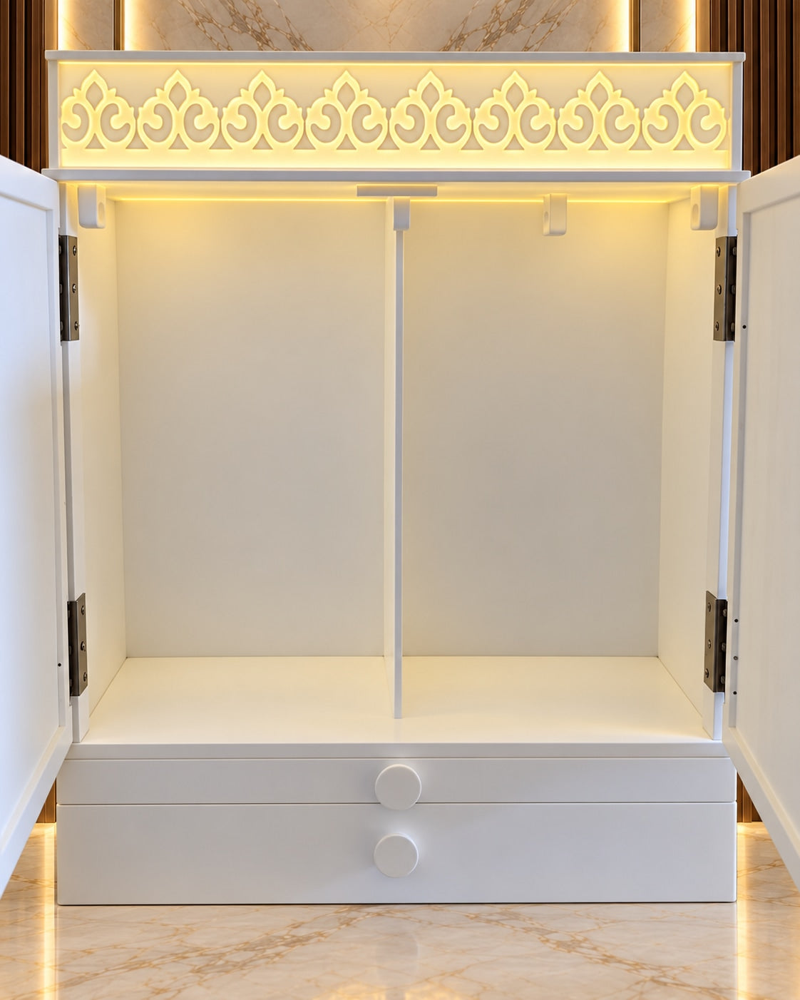 Open-door detail of a compact white Corian Jain mandir showing the plain illuminated interior, central divider and two drawers.